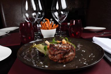 Pirzola bifteği, mevsimlik sebzeler ve arka planda patates kızartması. Restoran masasında servis edilen lüks yemek tabağı. Taze etli biftek.
