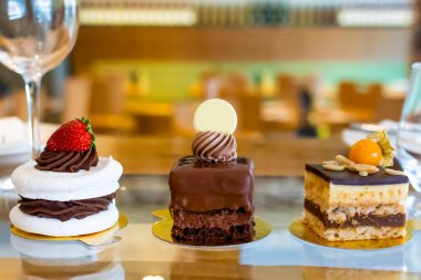 Tatlı seçimi: amandine, çikolatalı ve çilekli krema, karamel kek, restoran ortamında, bulanık arkaplan