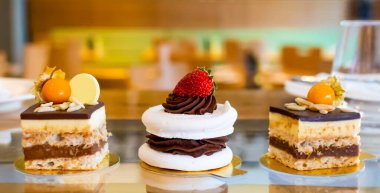 Üzerinde koyu çikolata ve çilek olan kremalı pasta, aristaurant bir ortamda, bulanık arka planda.