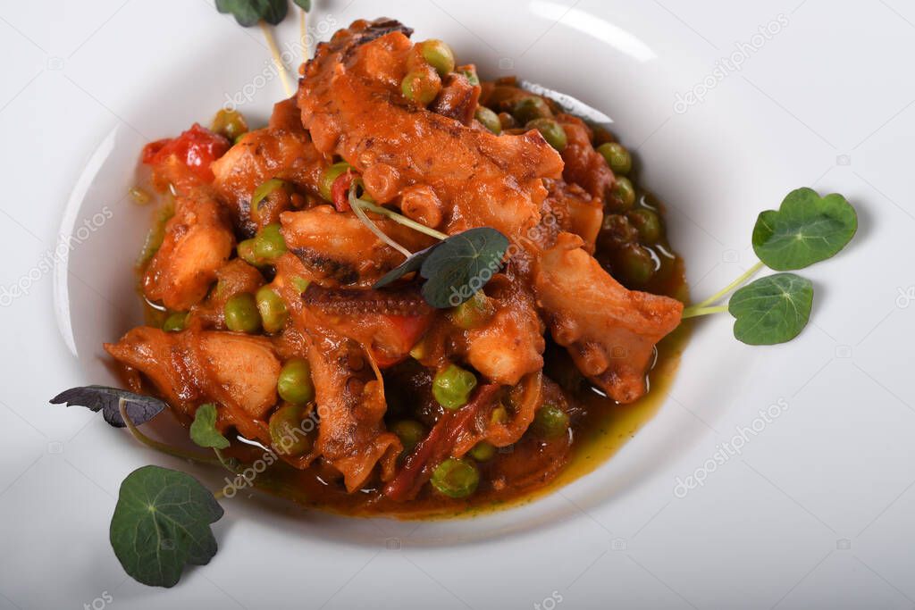 Polpo alla diavola. Octopus with tomato sauce served in a white plate, closeup view. Traditional italian dish, authentic recipe