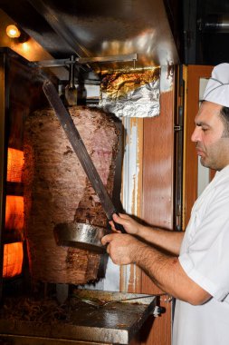 İstanbul, Türkiye, 20.12.2019: Şişe üzerinde shawarma kebabı kesen adam