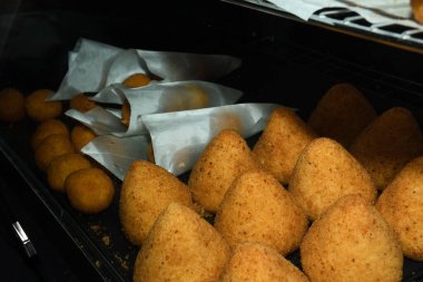 Arancini (bol etli kızarmış pirinç topları) İtalya 'daki markette tipik Sicilya sokak yemekleri. Sokak yemeklerinde satılacak bir sürü kızarmış pirinç topları.