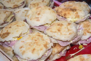 Tezgahta satılık farklı sandviçler, fast food sokak yemekleri festivali atıştırmalıkları. Jambon, peynir, ekmek burgeri.