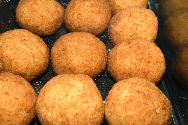 Arancini (deep fried rice balls with meat) Typical Sicilian street food at market in Italy. Lots of fried rice balls for sale in street food stall