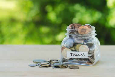 Seyahat tasarruf \ Money(coins) bir kavanoza bir tablo açık havada, yeşil arka plan