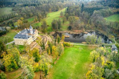 Sonbahar renklerinde kırmızı renkte muhteşem bir kale ve yanında da göl var.