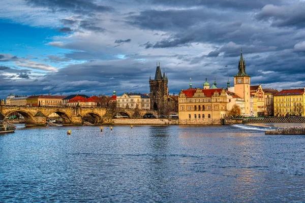 Bellamente iluminado Puente de Carlos al atardecer con los edificios circundantes, Praga —  Fotos de Stock