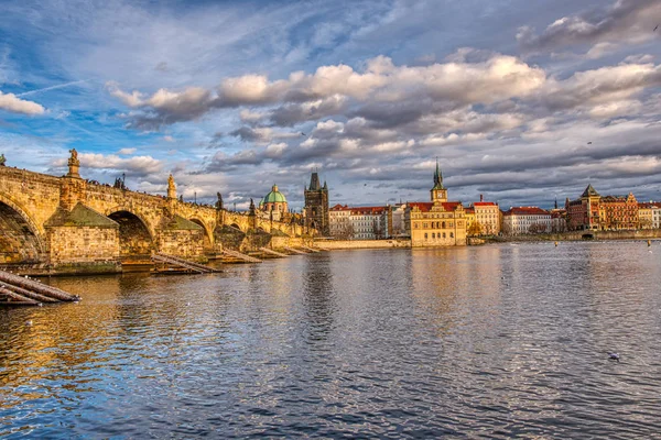Прекрасно освітлений міст Карла під час заходу сонця з довколишніми будівлями (Прага). — стокове фото