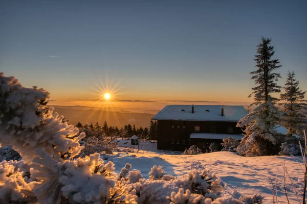 Luz dorada del sol sobre un idílico paisaje de invierno blanco con una pequeña cabaña de madera en el fondo, lysa hora checa — Foto de Stock