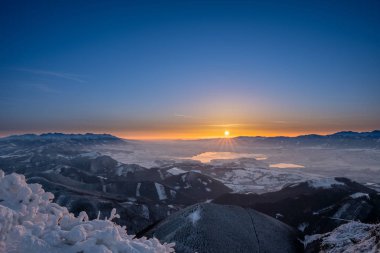 Kış mevsiminde Velky Choc dağından güneşin doğuşunu kaplayan karlar alçak ve yüksek Tatras ve Liptovska Mara, Slovakya manzaralı