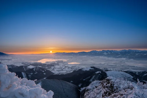 snow covered landscape sunrise sun from Velky Choc mountain in winter, with view of low and high Tatras and Liptovska Mara, slovakia