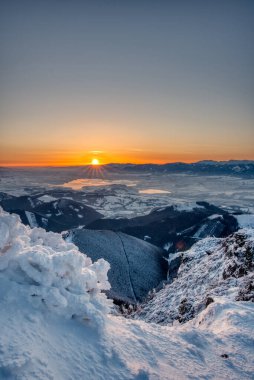 Kış mevsiminde Velky Choc dağından güneşin doğuşunu kaplayan karlar alçak ve yüksek Tatras ve Liptovska Mara, Slovakya manzaralı