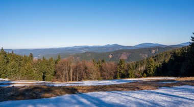 Kışın sonunda çayırlarda kar ve arka planda dağlar, besbelli czech