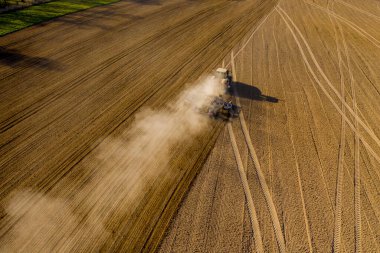 Çiftçinin traktördeki hava görüntüsü tohum ekiciyle toprağı hazırlarken, sabah güneşi...