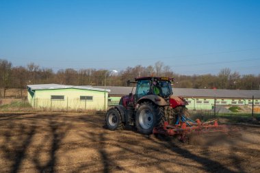 Traktördeki çiftçi tohum ekiciyle toprağı hazırlıyor, sabah güneşi...