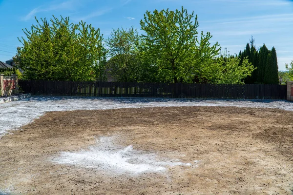 White lime is scattered on black soil. Adding lime to the soil to reduce its acidity, pH regulation of the soil balance