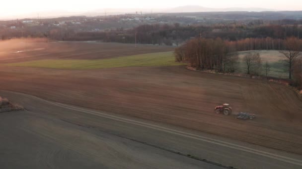 Traktörün hava görüntüsü akşamları kara toprağı besler. Sonbaharda kurak mevsimde traktörle kırsal alanda tarım faaliyetleri — Stok video