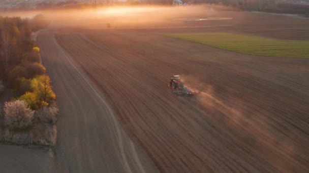 Traktorkultivator plöjer marken, förbereder sig för grödor. damm på fältet på morgonen soluppgång — Stockvideo