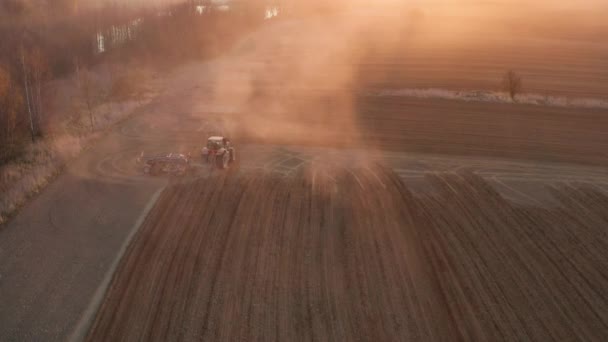 Erős, energiával telített, nagy kampóerővel rendelkező traktor légi kilátása, amely az őszi napfelkeltekor korongkultivátorral veti el a téli növényeket — Stock videók