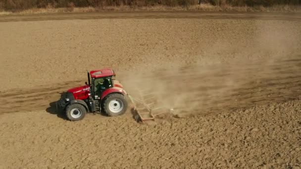 Stonava, Czech - 08. dubna 2020: Traktor obdělává půdu a osévá suché pole. Farmář připravuje půdu se semenným kultivátorem v rámci předsevu na začátku jarního období. — Stock video