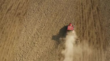 Traktör yağmur öncesi hazırlık için arazi ekme makinesini çekiyor. Bulutlu bahar günü. 4K hava görüntüsü.