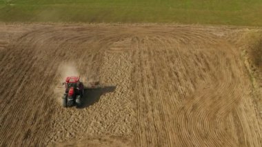 Tarla tarlasında tarlaları kesen traktörün havadan görünüşü. Tarım traktörü için roter harrow sabanı ekmeye hazırlanıyor..