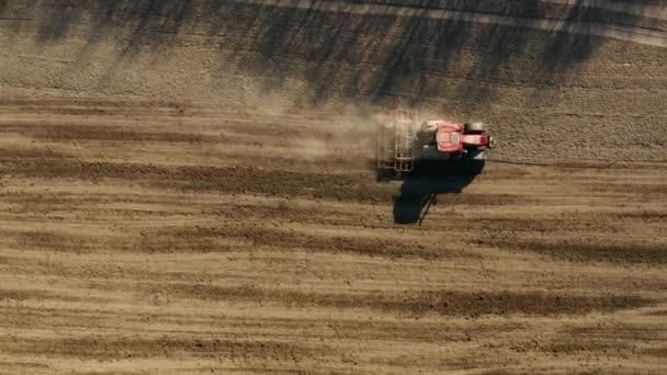 Traktor som odlar mark och sår ett torrt fält. Jordbrukare som förbereder mark med såbäddskultivator som en del av försåddsaktiviteter tidigt på våren. — Stockvideo