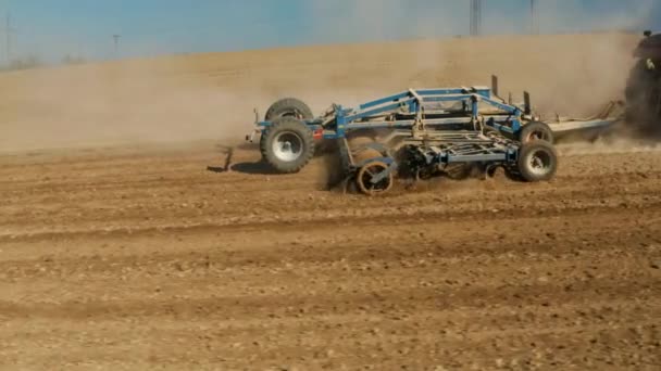 Elölnézet, a traktor szántja a földet, felkészül a terményekre. por a mezőn. A traktor szántja a poros száraz talajt. A termesztő szántja a földet, egy mezőn dolgozik. Mezőgazdasági termények vetése szántóföldön — Stock videók