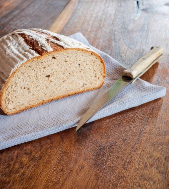 Eski ahşap masadaki lezzetli, kabuklu ekmeğe yaklaş