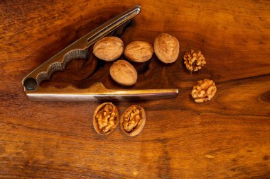 Tahta arka planda gümüş fındık kıracağı olan cevizler. İngilizce ve Farsça ceviz ağaçları arasındaki bir çapraz kaynaktan geliyor..