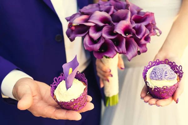 Buquê de casamento e bolos são roxos nas mãos . — Fotografia de Stock