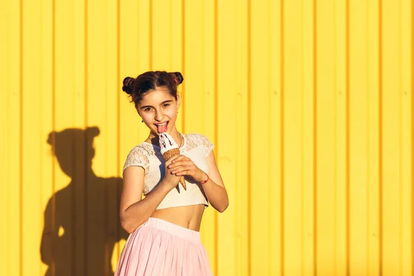 Retrato de una chica sonriente con helado en las manos en una b amarilla — Foto de Stock