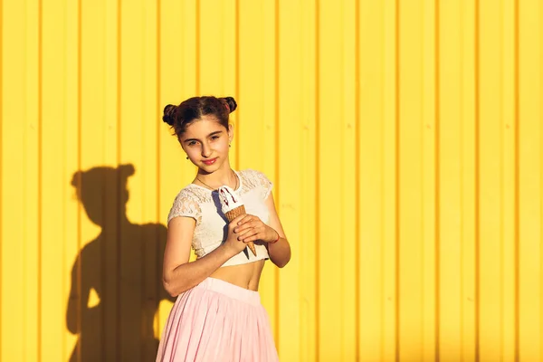 Retrato de una chica sonriente con helado en las manos en una b amarilla — Foto de Stock