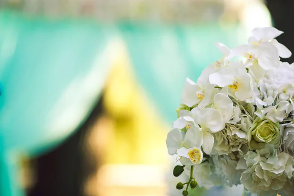 Um buquê de orquídeas brancas contra um arco de casamento azul . — Fotografia de Stock