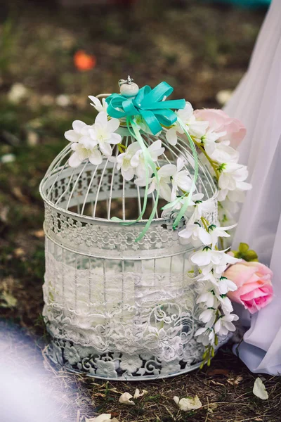 Decoração no casamento: uma gaiola de pássaro decorada com orquídeas e tecido de renda . — Fotografia de Stock