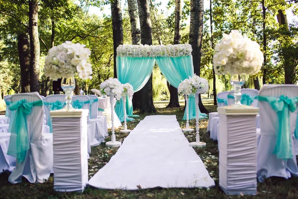 A decoração da cerimônia de casamento em cores azuis de verão no parque: um arco, cadeiras, flores, caminho . — Fotografia de Stock