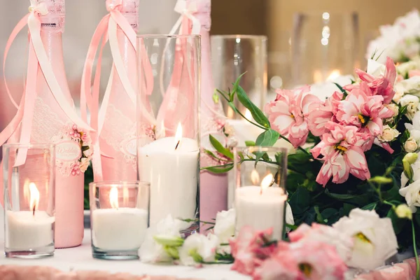 Decoração em rosa na mesa de casamento: garrafas de champanhe, velas, flores . — Fotografia de Stock