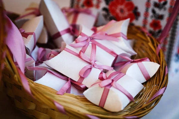 Caixas de presente com arcos rosa encontram-se em uma cesta de vime . — Fotografia de Stock