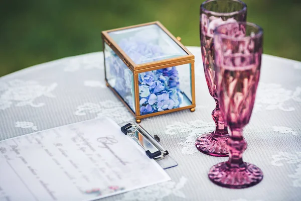 Dois copos, um certificado de casamento e uma decoração floral na mesa. Decorações de casamento . — Fotografia de Stock