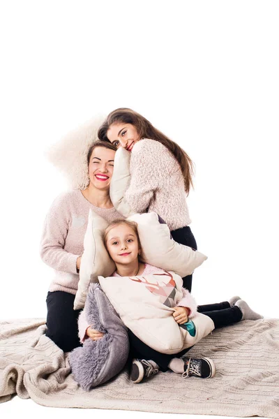 Mamá y dos hijas con almohadas se sientan y alegremente abrazan . — Foto de Stock