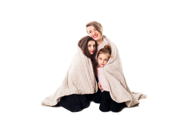 Мама и две дочери сидят и обнимаются под одеялом . — стоковое фото