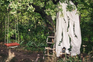 Dekorasyon düğün için: ip salıncak, siyah fenerler, Ivy twigs, sazlık, merdiven, beyaz kumaş, çiçek üzerinde meşe.