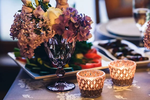 Decoração na mesa: velas em óculos, flores roxas em vasos — Fotografia de Stock