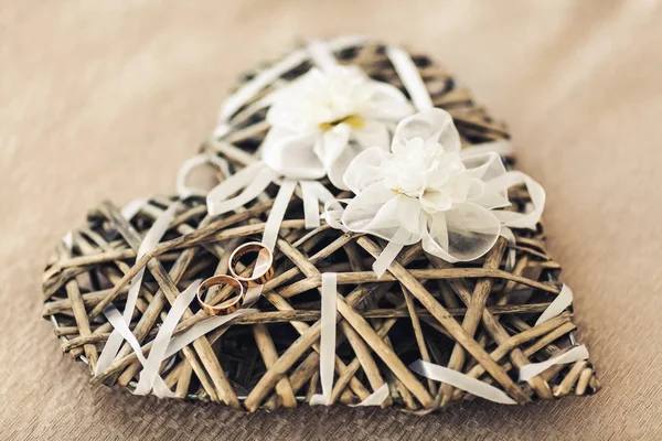 Anéis de casamento encontram-se no coração decorativo da videira, decorado com flores artificiais — Fotografia de Stock