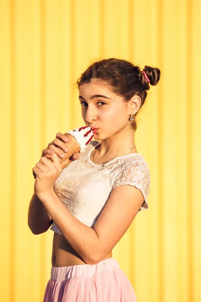 Feliz elegante chica en rosa falda besos un helado en amarillo fondo de la pared . — Foto de Stock