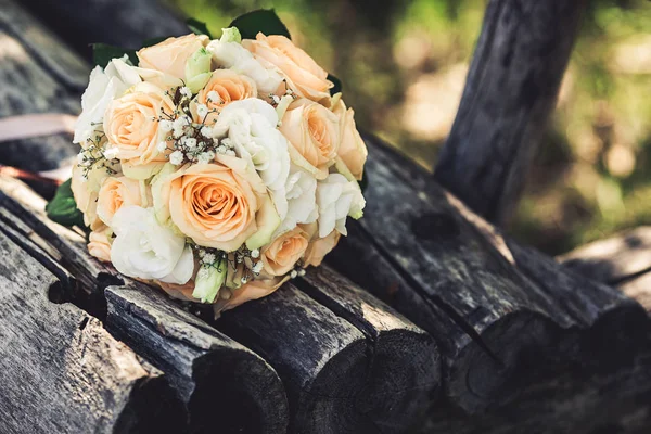 Um buquê de casamento de rosas brancas e laranja em um banco — Fotografia de Stock