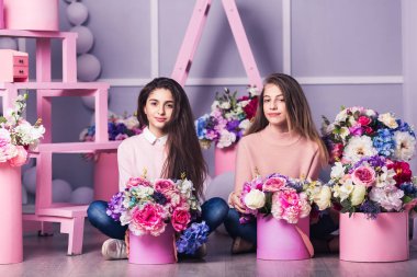 İki güzel kız kot pantolon ve Studio dekor çiçek sepetleri ile pembe kazak.