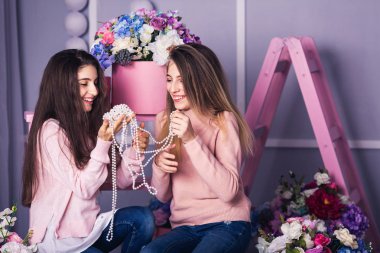 İki güzel kız kot pantolon ve pembe kazak boncuk Studio dekor çiçek sepetleri ile tutuyorsun.