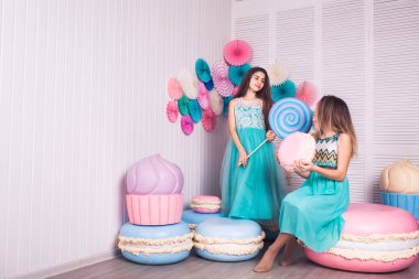 İki güzel kız mavi elbiseler eller büyük şeker ve Studio acıbadem kurabiyesi macaroons dekora tutun
