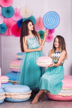 İki güzel kız mavi elbiseler eller büyük şeker ve Studio acıbadem kurabiyesi macaroons dekora tutun